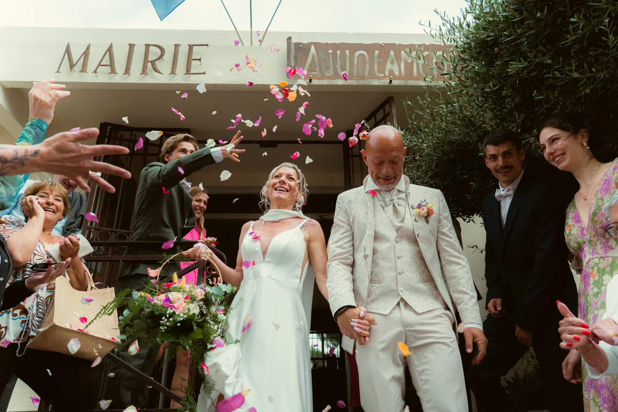 Sortie de mairie sous les pétales de fleurs, mariés main dans la main